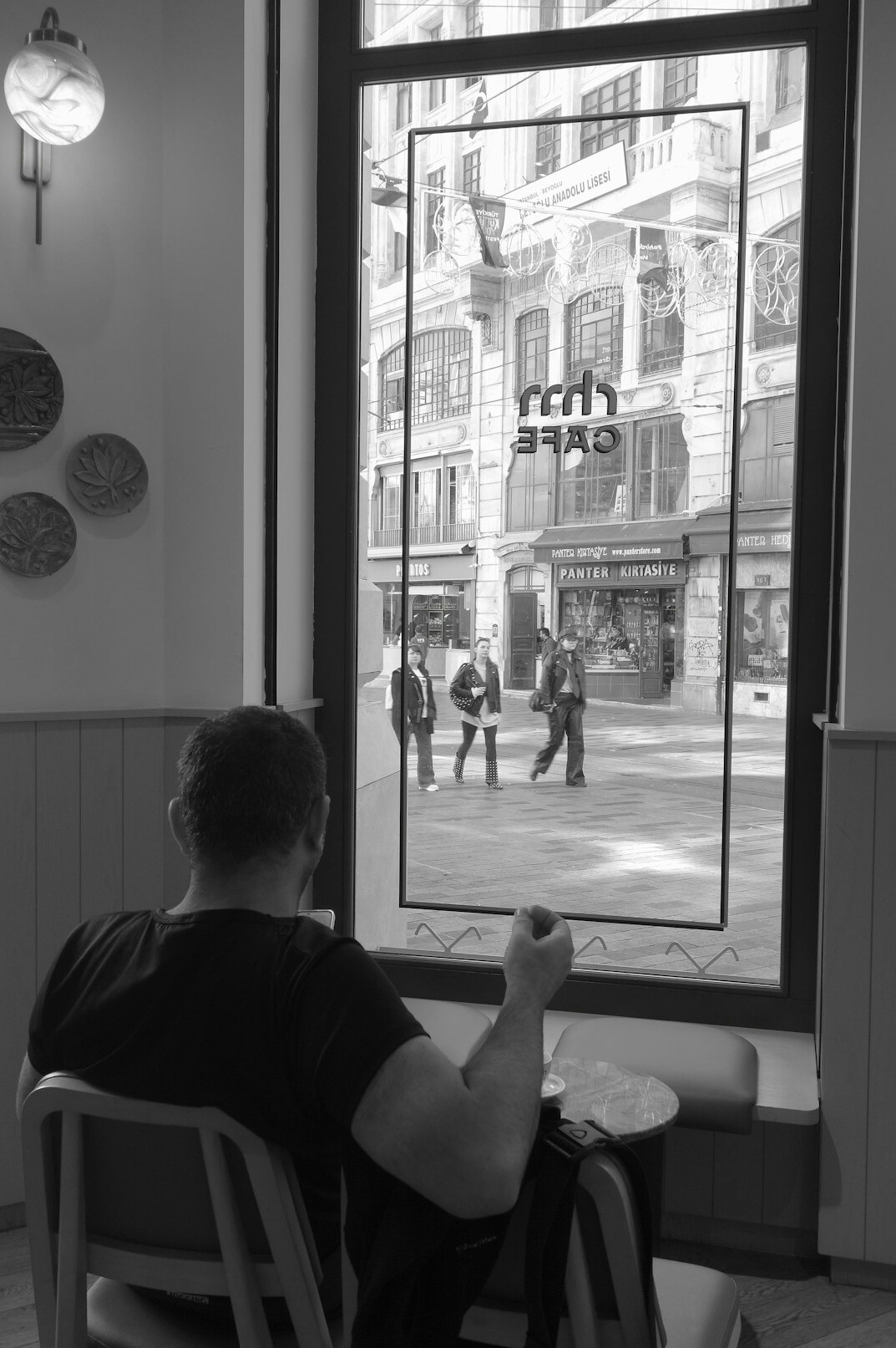 Person sitting by a cafe window watching the street