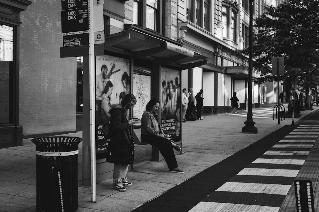 people waiting at bus stop in city