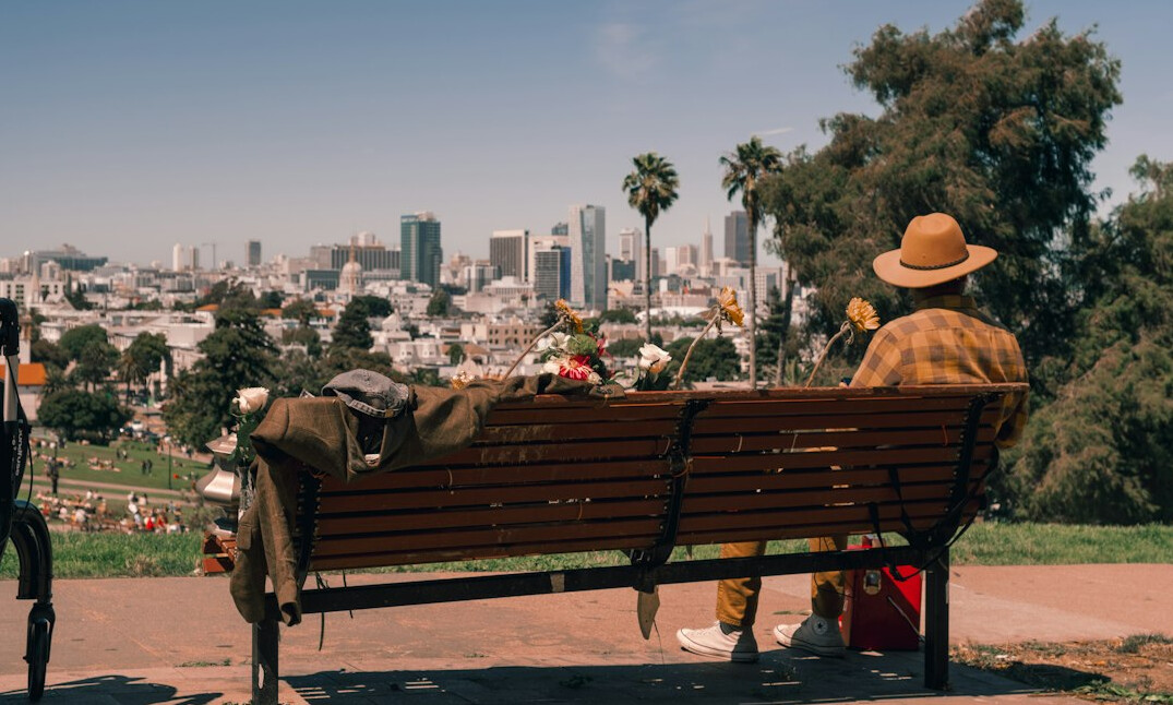 Two people sitting on a park bench in a city