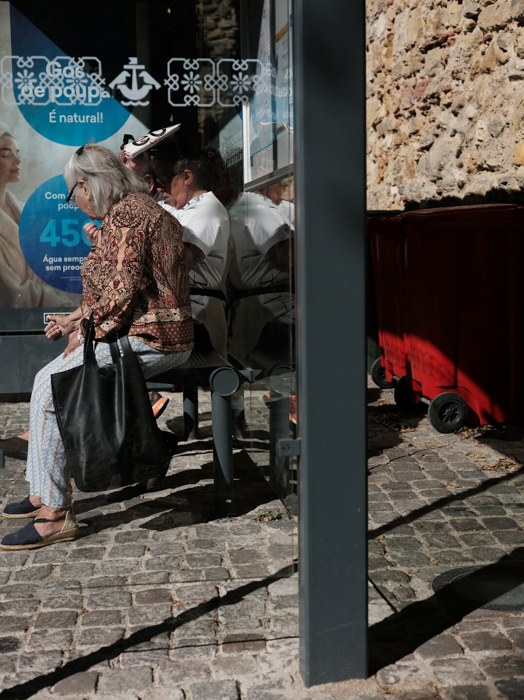 elderly man sharing umbrella at bus stop